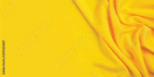A soft flowing yellow silk fabric backdrop with a smooth golden satin texture and shiny drapery curves creating a luxury material pattern