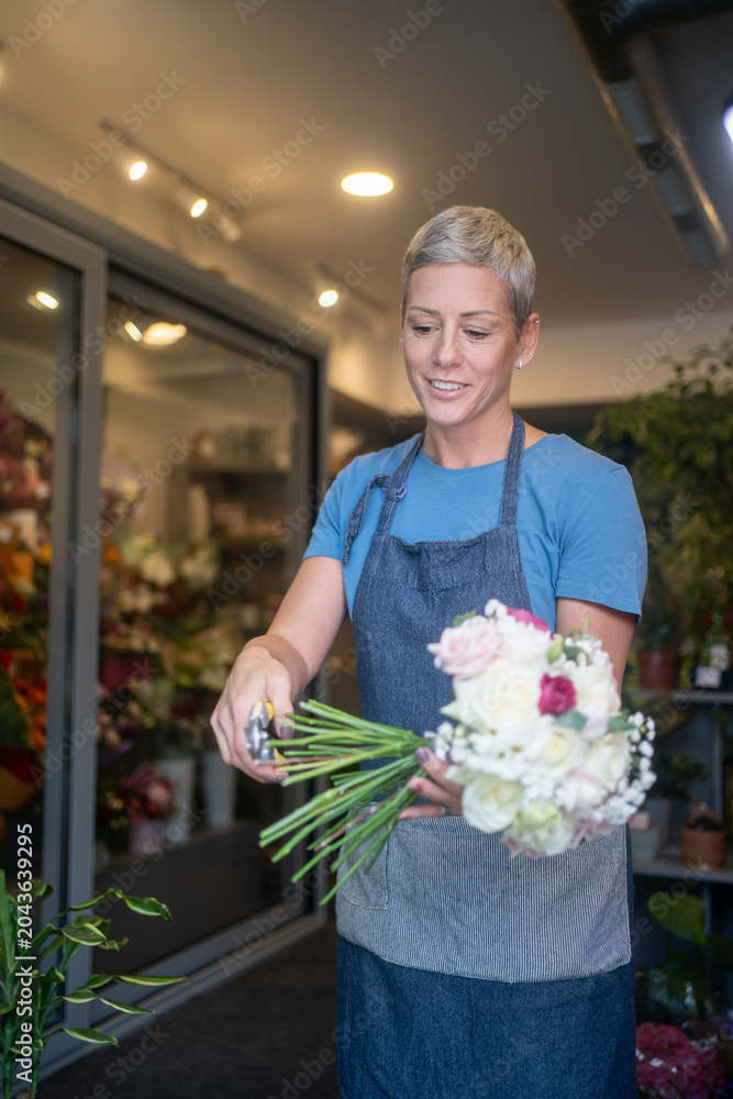 Fototapeta premium Female florist arranging cut flowers for retail display