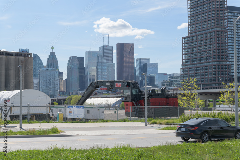 Naklejka premium heavy machinery at Cherry Street Yard with view of Toronto's cityscape