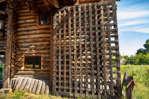 Tall wooden gates of a wooden fortress. Wooden walls made of round chopped logs of a reconstructed Old Slavic fortress. Bright sunny day.