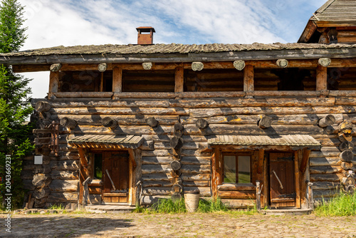 The impressive wooden walls of a reconstructed Old Slavic fortress, made of round, hewn logs. Old barracks and boyar chambers. A bright, sunny day.