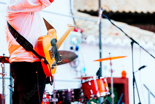 Guitarist performing live with electric guitar, drummer and band on stage