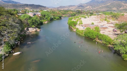 Stunning aerial perspective of a scenic river in Tecpan de Galeana, Guerrero, Mexico, where people enjoy swimming in its fresh waters on a warm day.
