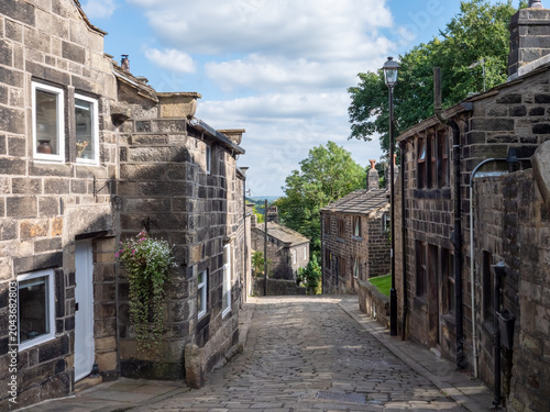 Town gate the main street in the historic village of Heptonstall in summer with the cobbled road surrounded by old stone houses in summer