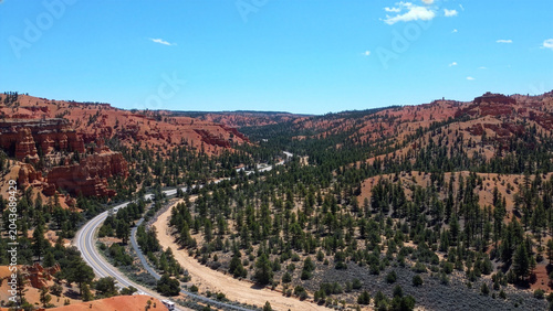 Foto Breathtaking bird's-eye view of a modern asphalt highway cutting through lush green valleys and forests in Dixie National Forest, Utah