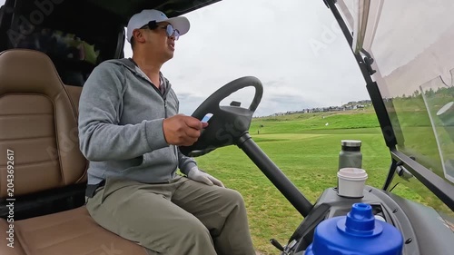 Asian man in hat driving the golf power cart in Kelowna