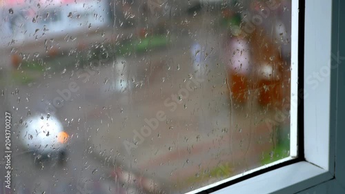 Raindrops on Window Glass with Blurred Cars Passing in Rainy Residential Street