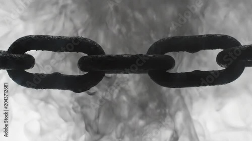 A close-up view of a rusty chain links against a smoky background.