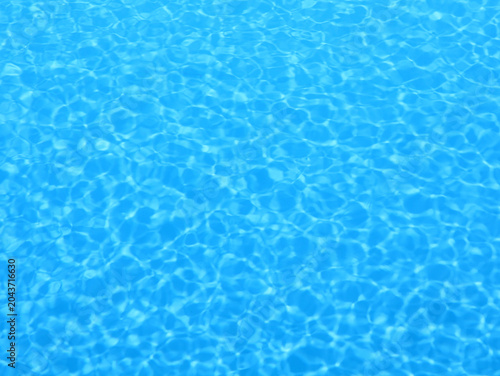 Sparkling blue pool water with light reflections. Background for summer themes.