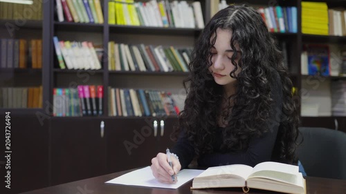 Teenage student girl working with a book in the school library
