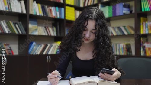 Teenage student girl working with a book in the school library
