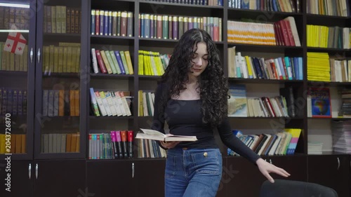 Teenage student girl working with a book in the school library