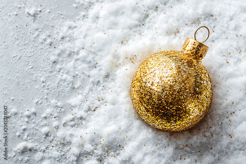 Celebrate the season with a shimmering golden ornament resting on snow, bringing a touch of magic and warmth to your holiday projects