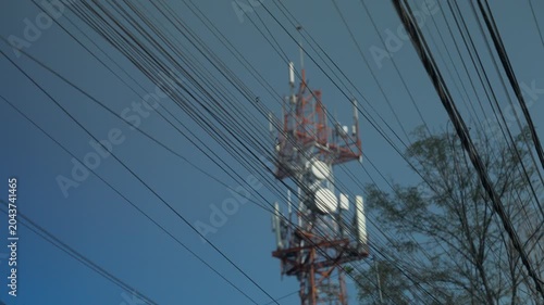 Cell phone tower antenna behind tangled power lines in Latin American urban area