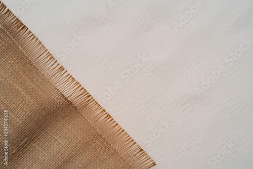 A close-up view of a woven fabric's frayed edge on a smooth surface