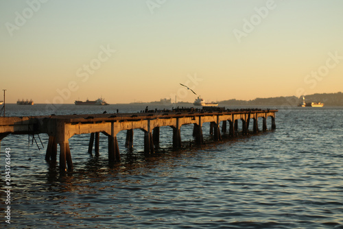 Fotografie Old wooden pier extending into calm water at sunset