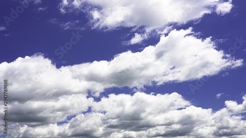 Beautiful white cumulus clouds gracefully floating across a vibrant deep blue sky on a sunny day. Clean atmosphere and pleasant weather
