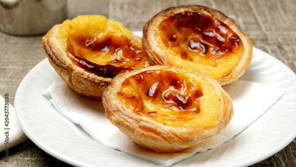 Fototapeta premium Three Freshly Baked Portuguese Custard Tarts Served on a White Plate