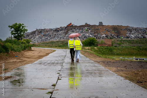 A young couple is walking past a landfill near the city