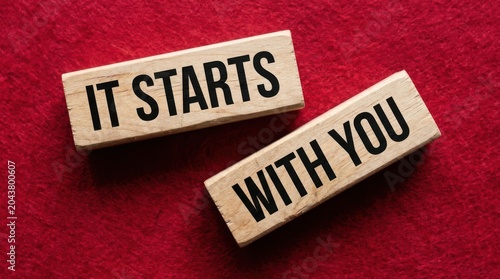 Two wooden rectangular blocks with printed text it starts with you placed on bright vibrant textured red background.