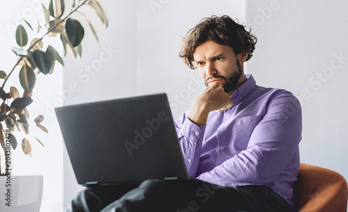 Foto A man is seated in a chair while looking intently at a laptop