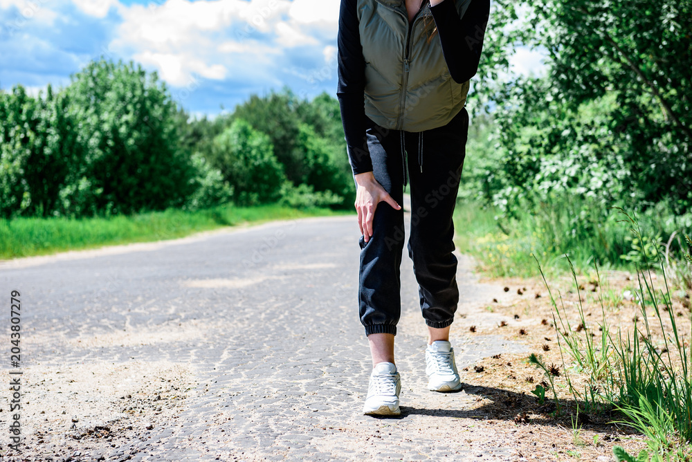 Naklejka premium Young woman with knee pain during running.