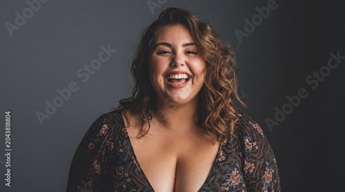 Cheerful body positive plus size mid adult woman laughing during studio portrait