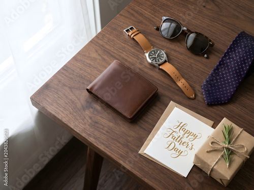 Top-down Flat Lay of Stylish Wristwatch, Leather Wallet, Sunglasses, Necktie, Greeting Card, and Gift Box on Wooden Surface, Elegant Father's Day Premium Lifestyle Branding Image