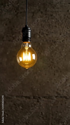Vintage edison light bulb hanging against dark concrete wall background