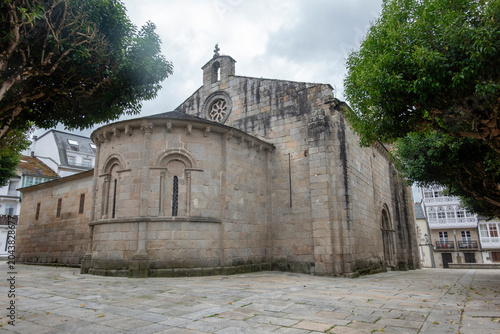 Tableau sur toile The ancient Romanesque apse and stone architecture of the Church of Santa Maria do Campo in Viveiro, Galicia, Spain, surrounded by green trees on a cloudy day