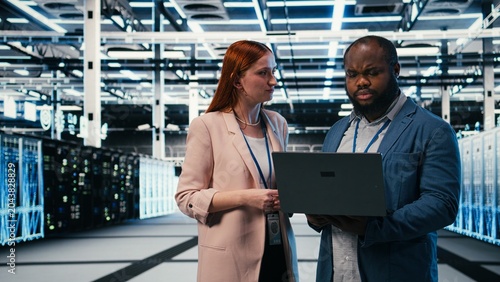 Photography Optimizing electronics, laptop and manager teaching intern in server farm during induction, Monitoring system performance, notebook and team leader with trainee in data center, camera A