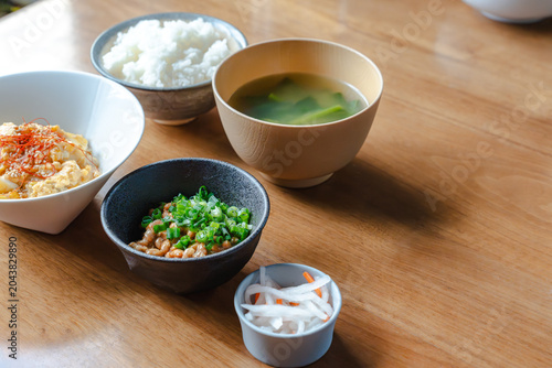 Bild auf Leinwand 木製テーブル上の納豆や味噌汁などの和食朝食セットと右側のコピースペース。フードメディアや広告デザイン用