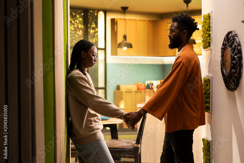 Foto African American couple holding hands and making up after fight at home, sharing a tender emotional reunion, Man and woman show forgiveness, rebuilding trust and peaceful harmony
