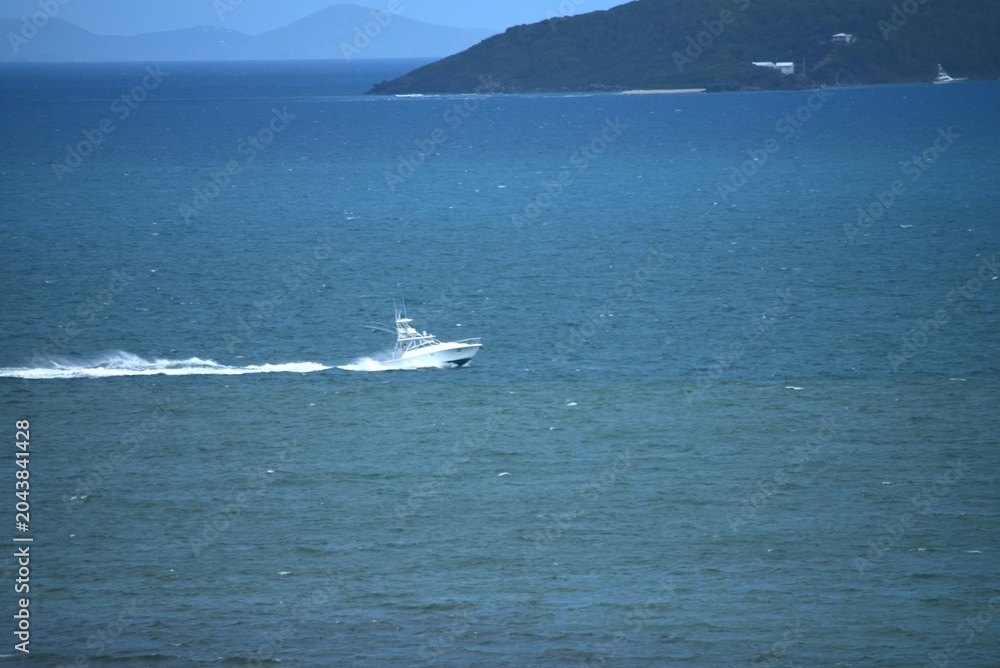 Fototapeta premium Hermosa vista costera en Puerto Rico con olas suaves llegando a la orilla y pequeñas embarcaciones visibles en el horizonte. Un paisaje marino tranquilo que refleja la belleza natural del Caribe, idea