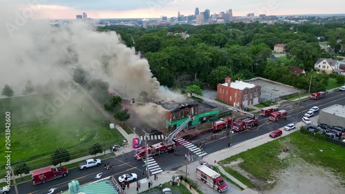 aerial view of firefighters extinguishing building fire in front of city skyline