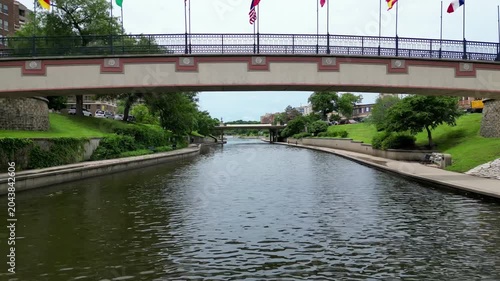 flying low under bridge with flags over canal