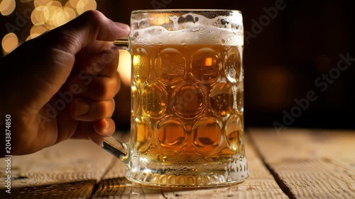 Hand Holds Refreshing Beer Mug Near Cozy Fireplace - Warmth and Relaxation.