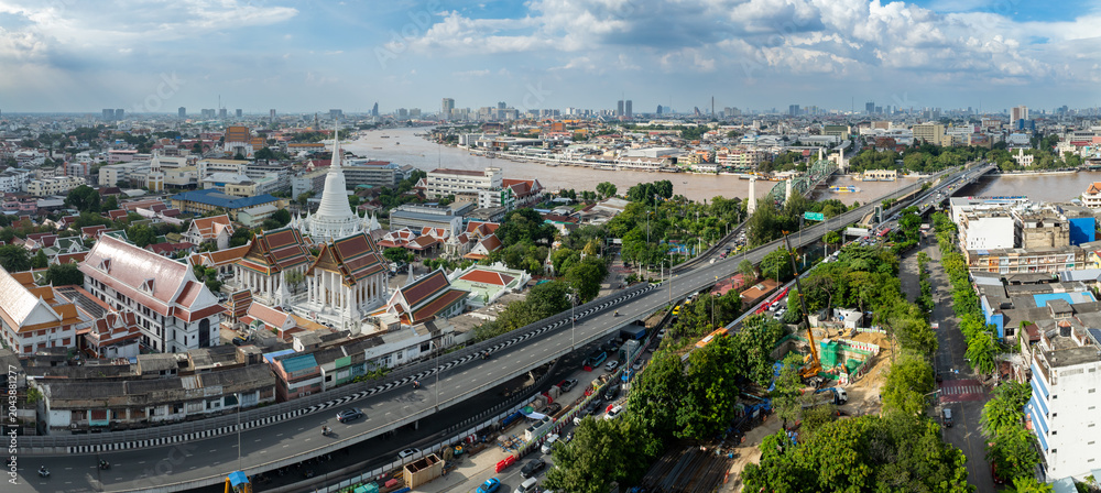 Fototapeta premium Bangkok, Thailand - A panoramic view of the Chao Phraya River and city skyline, featuring Wat Arun and a busy highway.