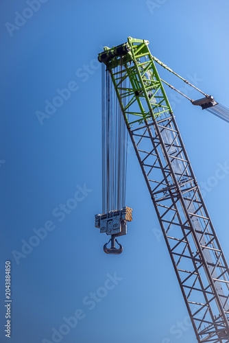 Industrial crane, steel cables and pulleys. boom and hook. harbor crane. Blue sky background.