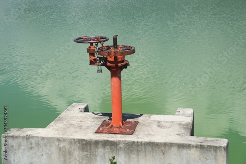 Obraz na płótnie Water Gate Valve Mechanism :
An aged red iron sluice gate control valve or wate