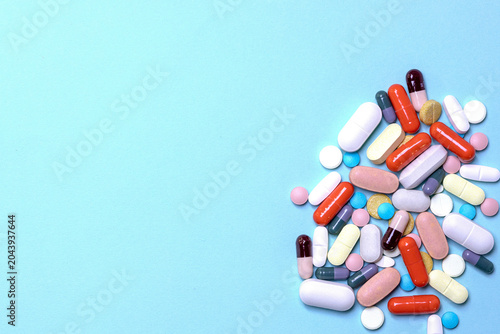 Canvastavla Top view of a pile of various medications on a blue surface; concept of healthcare, pharmacy, and medical treatment