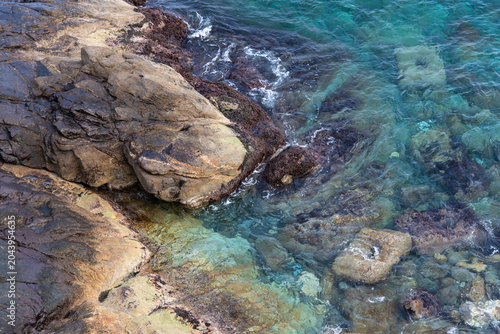 Top view of transparent emerald sea water and coastal rocks