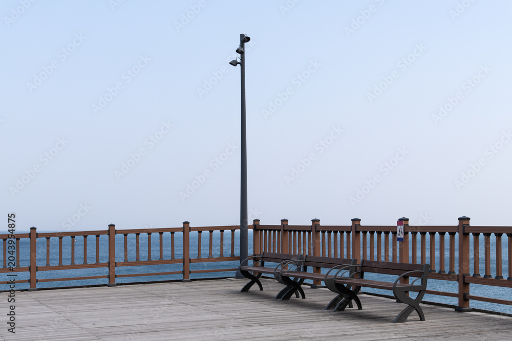 Naklejka premium Wooden ocean observatory deck with empty benches and street lamp