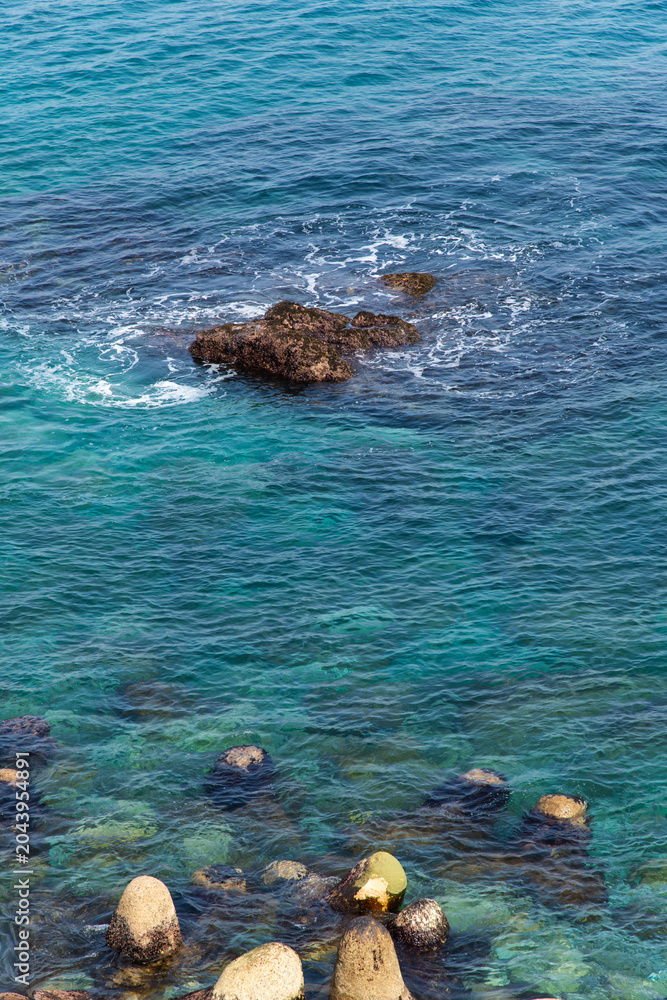 Obraz premium Clear coastal water with tetrapods and underwater rocks