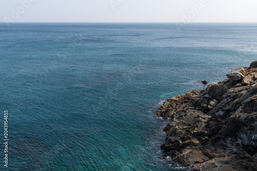 Rocky cliff shoreline meeting the deep blue ocean horizon