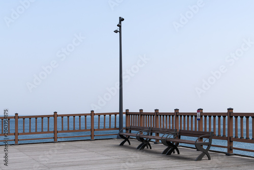 Wooden ocean observatory deck with empty benches and street lamp