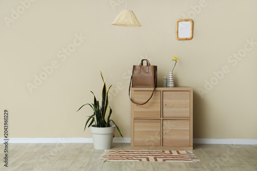 Foto Interior of room with stylish bag on commode and plant