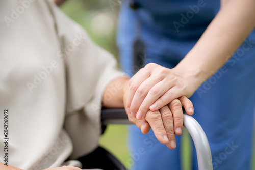 Close up nurse holding hand senior patient for encourage, assistance and support, caregiver touch hand elderly woman with empathy and comfort, rehabilitation therapy mental health for elderly.