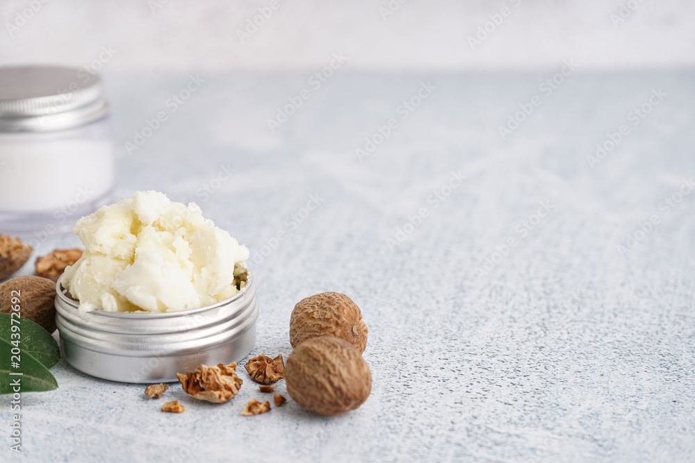 Obraz premium Jar of shea butter with nuts on grunge background, closeup