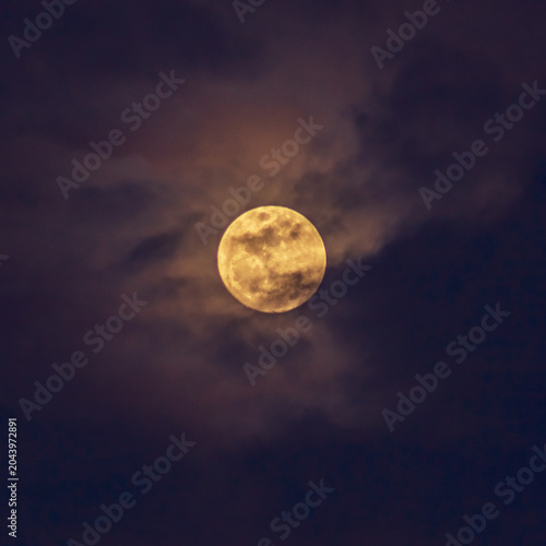 Super full moon in the night sky with clouds, natural background.